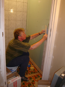 De muur van de WC wordt getegeld